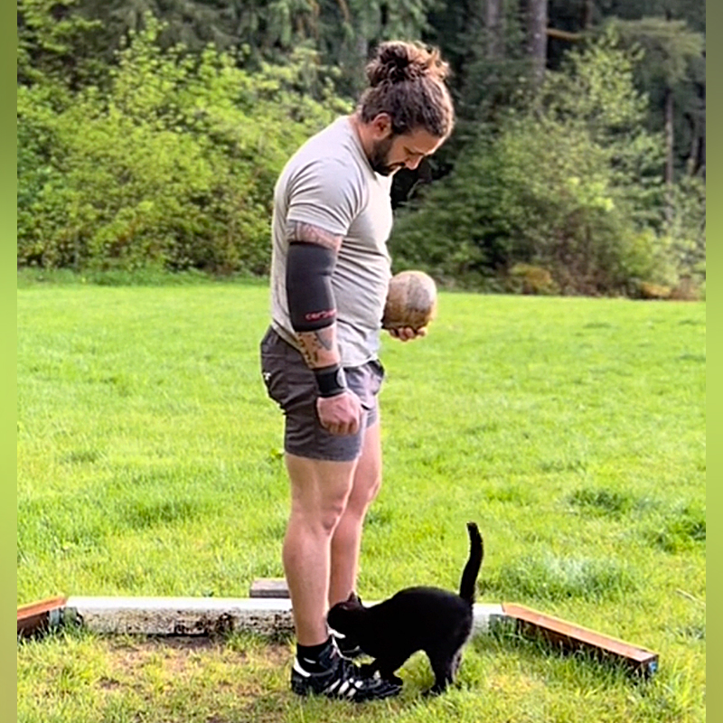 Nathan L. Western Washington, Punkin the black cat, Riley the Yellow Labrador Retriever, cat interrupts Dad's workouts and training, weight toss, hammer toss, Backwoods Highlander, black cat walks up to Dad who is throwing rocks